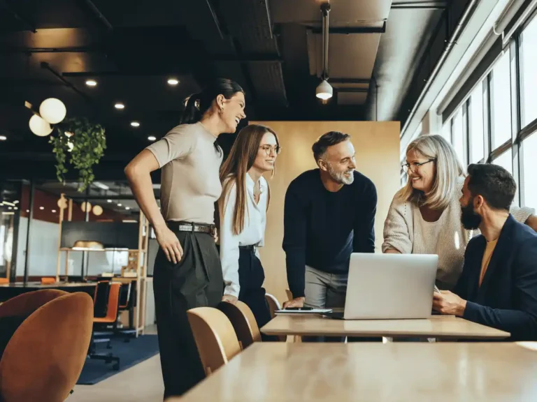 Team of employees collaborating together around a laptop